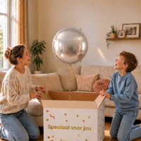 Moeder en jongen pakken een zilveren ronde heliumballon van 45 cm uit de cadeauverpakking.