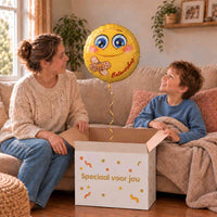 Moeder en kind pakken samen een gele Smiley beterschap-ballon van 45 cm uit in een warme woonkamer