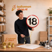 Jesse houdt de Ballon Verkeersbord 18 Jaar vast in de warme werkplaats van Ballonnenshop.nl.