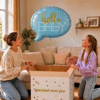 Hello Baby Blauw Helium Ballon zweeft boven een geopende cadeaudoos bij een moeder en meisje in een warme woonkamer.