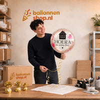 Jesse houdt de Hoera Een Nieuw Huis Ballon vast in de warme werkplaats van Ballonnenshop.nl.