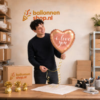Jesse houdt de I Love You Ballon Rose Goud vast in de warme werkplaats van Ballonnenshop.nl.