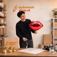 Jesse houdt de I Love You Kus Ballon vast in de warme werkplaats van Ballonnenshop.nl.