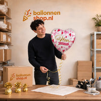 Jesse houdt de Ik Hou Van Jou Helium Ballon vast in de warme werkplaats van Ballonnenshop.nl.