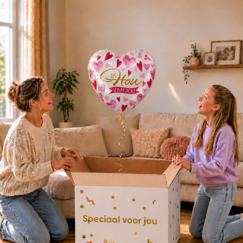 Moeder en dochter openen een cadeaudoos met een Ik Hou Van Jou hartballon van 43 cm met roze hartjes.
