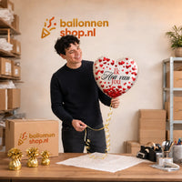 Jesse houdt de Ik Hou Van Jou Hartjes Ballon vast in de warme werkplaats van Ballonnenshop.nl.