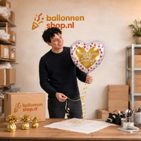 Jesse houdt de Je Bent Goud Waard Helium Ballon vast in de warme werkplaats van Ballonnenshop.nl.
