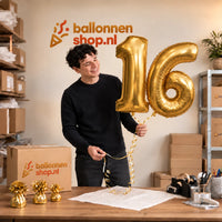 Jesse houdt de 16 Jaar Cijfer Ballonnen Goud vast in de warme inpakruimte van Ballonnenshop.nl.