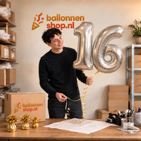 Jesse houdt de 16 Jaar Cijfer Ballonnen Zilver vast in de warme inpakruimte van Ballonnenshop.nl.