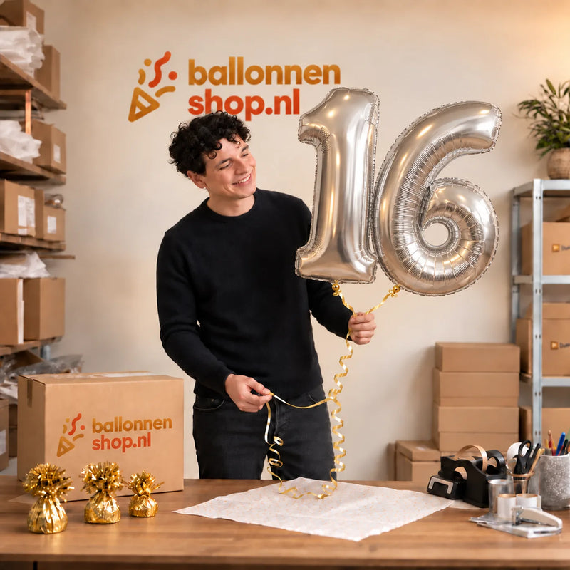 Jesse houdt de 16 Jaar Cijfer Ballonnen Zilver vast in de warme inpakruimte van Ballonnenshop.nl.