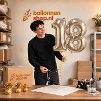 Jesse houdt de 18 Jaar Cijfer Ballonnen Zilver vast in de warme inpakruimte van Ballonnenshop.nl.