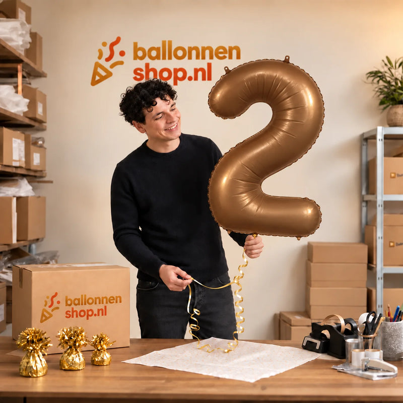 Jesse houdt de 2 Jaar Cijfer Bruin XL Ballon vast in de warme inpakruimte van Ballonnenshop.nl.