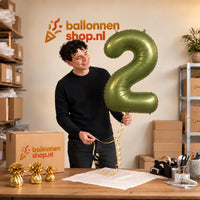 Jesse houdt de 2 Jaar Cijfer Groen XL Ballon vast in de warme inpakruimte van Ballonnenshop.nl.