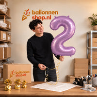 Jesse houdt de 2 Jaar Cijfer Paars XL Ballon vast in de warme inpakruimte van Ballonnenshop.nl.