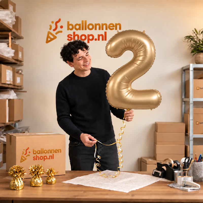 Jesse houdt de 2 Jaar Cijfer Starlight Goud XL vast in de warme inpakruimte van Ballonnenshop.nl.