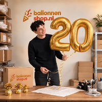 Jesse houdt de 20 Jaar Cijfer Ballonnen Goud vast in de warme inpakruimte van Ballonnenshop.nl.