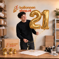 Jesse houdt de 21 Jaar Cijfer Ballonnen Goud vast in de warme inpakruimte van Ballonnenshop.nl.
