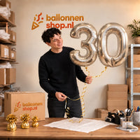 Jesse houdt de 30 Jaar Cijfer Ballonnen Zilver vast in de warme inpakruimte van Ballonnenshop.nl.