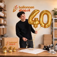 Jesse houdt de 40 Jaar Cijfer Ballonnen Goud vast in de warme inpakruimte van Ballonnenshop.nl.