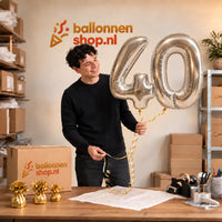 Jesse houdt de 40 Jaar Cijfer Ballonnen Zilver vast in de warme inpakruimte van Ballonnenshop.nl.