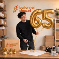 Jesse houdt de 65 Jaar Cijfer Ballonnen Goud vast in de warme inpakruimte van Ballonnenshop.nl.