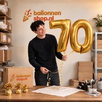 Jesse houdt de 70 Jaar Cijfer Ballonnen Goud vast in de warme inpakruimte van Ballonnenshop.nl.