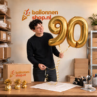 Jesse houdt de 90 Jaar Cijfer Ballonnen Goud vast in de warme inpakruimte van Ballonnenshop.nl.