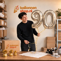 Jesse houdt de 90 Jaar Cijfer Ballonnen Zilver vast in de warme inpakruimte van Ballonnenshop.nl.