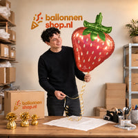 Jesse houdt de Aardbei Holographic Iridescent vast in de warme inpakruimte van Ballonnenshop.nl.