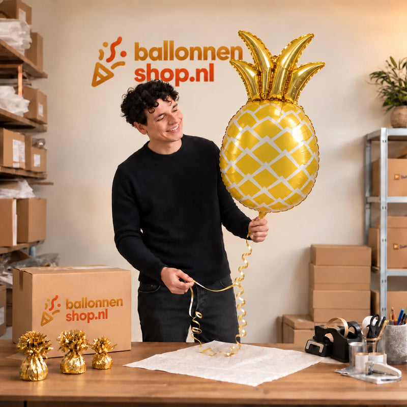 Jesse houdt de Ananas Helium Ballon vast in de warme inpakruimte van Ballonnenshop.nl.