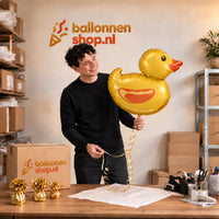 Jesse houdt de Badeend Helium Ballon vast in de warme inpakruimte van Ballonnenshop.nl.