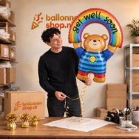 Jesse houdt de Beer Get Well Soon Regenboog XL vast in de warme inpakruimte van Ballonnenshop.nl.