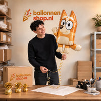 Jesse houdt de Bingo Bluey Helium XL Ballon vast in de warme inpakruimte van Ballonnenshop.nl.