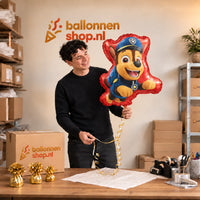 Jesse houdt de Chase Paw Patrol Helium Ballon vast in de warme inpakruimte van Ballonnenshop.nl.