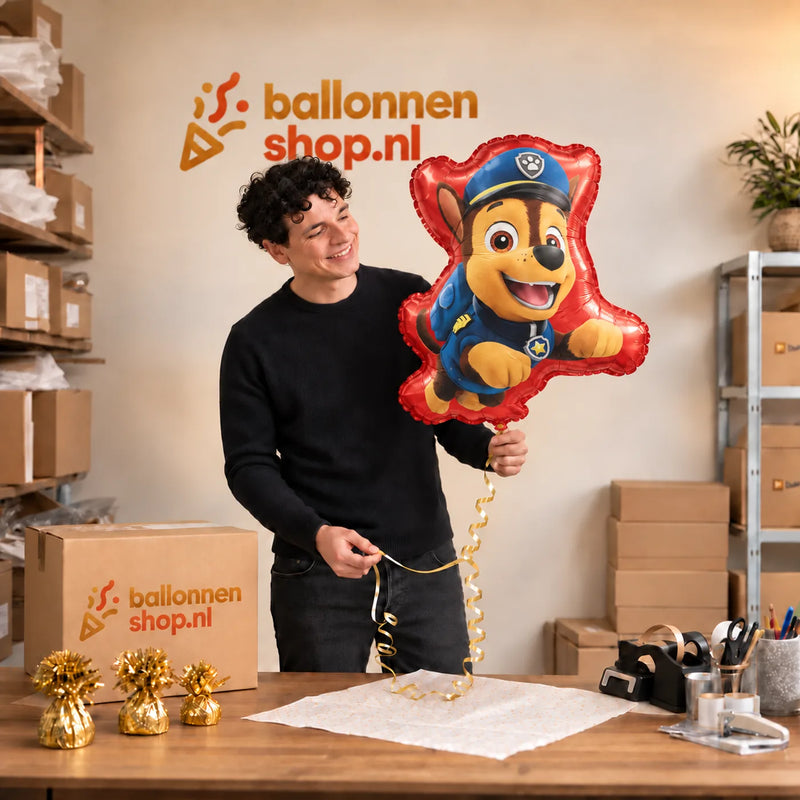 Jesse houdt de Chase Paw Patrol Helium Ballon vast in de warme inpakruimte van Ballonnenshop.nl.