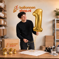 Jesse houdt de Cijfer 1 Helium Ballon Goud vast in de warme inpakruimte van Ballonnenshop.nl.