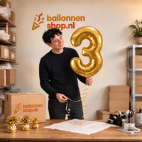 Jesse houdt de Cijfer 3 Helium Ballon Goud vast in de warme inpakruimte van Ballonnenshop.nl.