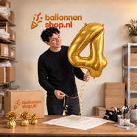 Jesse houdt de Cijfer 4 Helium Ballon Goud vast in de warme inpakruimte van Ballonnenshop.nl.