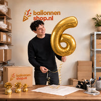 Jesse houdt de Cijfer 6 Helium Ballon Goud vast in de warme inpakruimte van Ballonnenshop.nl.