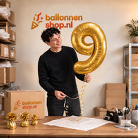Jesse houdt de Cijfer 9 Helium Ballon Goud vast in de warme inpakruimte van Ballonnenshop.nl.