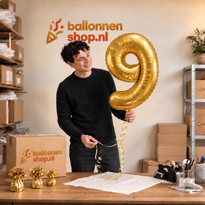 Jesse houdt de Cijfer 9 Helium Ballon Goud vast in de warme inpakruimte van Ballonnenshop.nl.