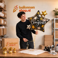 Jesse houdt de Congrats Ster Helium XL Ballon vast in de warme inpakruimte van Ballonnenshop.nl.