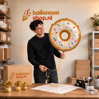 Jesse houdt de Donut Helium Ballon vast in de warme inpakruimte van Ballonnenshop.nl.