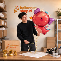 Jesse houdt de Draak Dino Helium XL Ballon vast in de warme inpakruimte van Ballonnenshop.nl.
