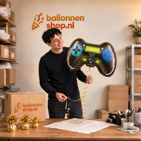 Jesse houdt de Game Controller Helium Ballon vast in de warme inpakruimte van Ballonnenshop.nl.