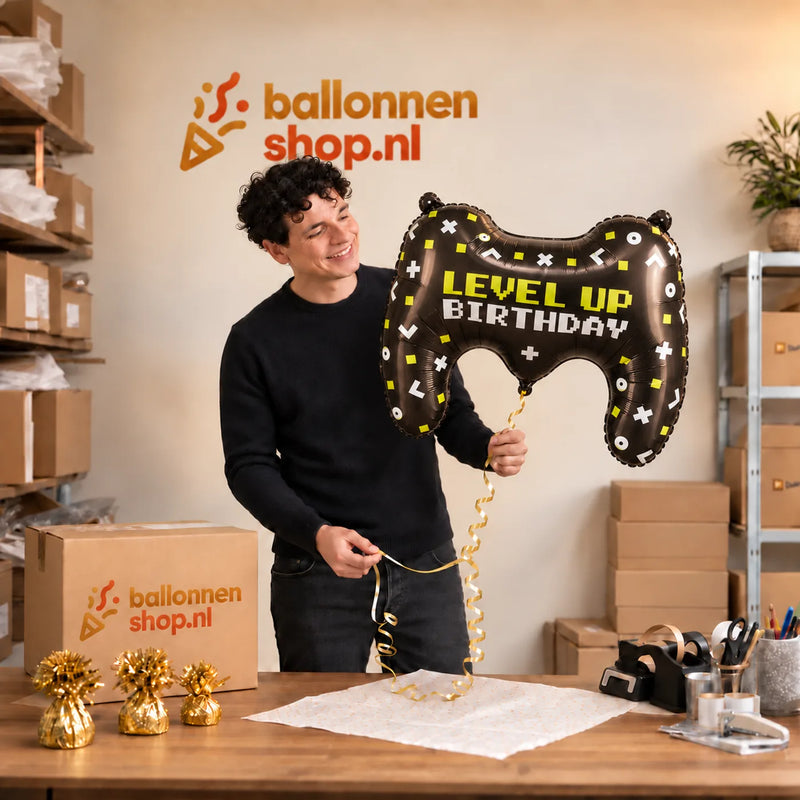 Jesse houdt de Gamecontroller Level Up XL Ballon vast in de warme inpakruimte van Ballonnenshop.nl.