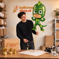 Jesse houdt de Gekko PJ Masks Helium XL Ballon vast in de warme inpakruimte van Ballonnenshop.nl.