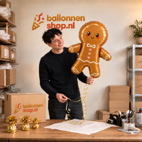 Jesse houdt de Gingerbread Mannetje XL Ballon vast in de warme inpakruimte van Ballonnenshop.nl.