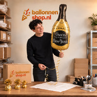 Jesse houdt de Glittering New Year XL Ballon vast in de warme inpakruimte van Ballonnenshop.nl.