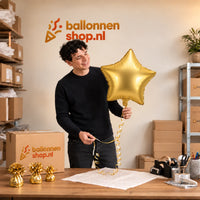 Jesse houdt de Gouden Ster Helium Ballon vast in de warme inpakruimte van Ballonnenshop.nl.